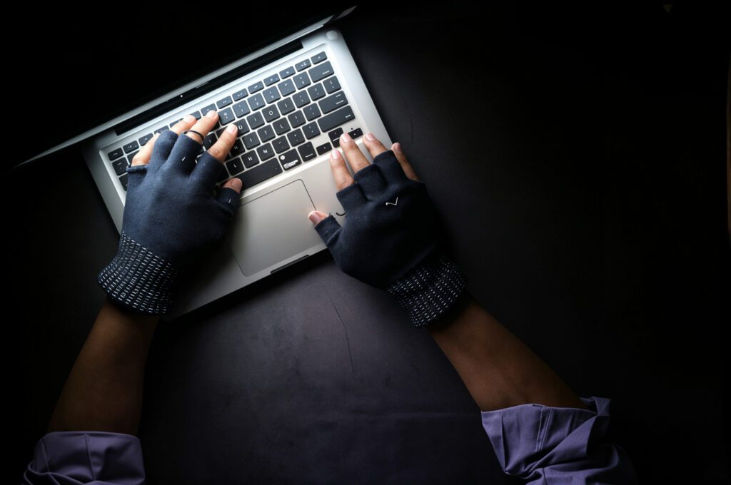 Scammer working in the dark on a laptop representing AI-driven scams