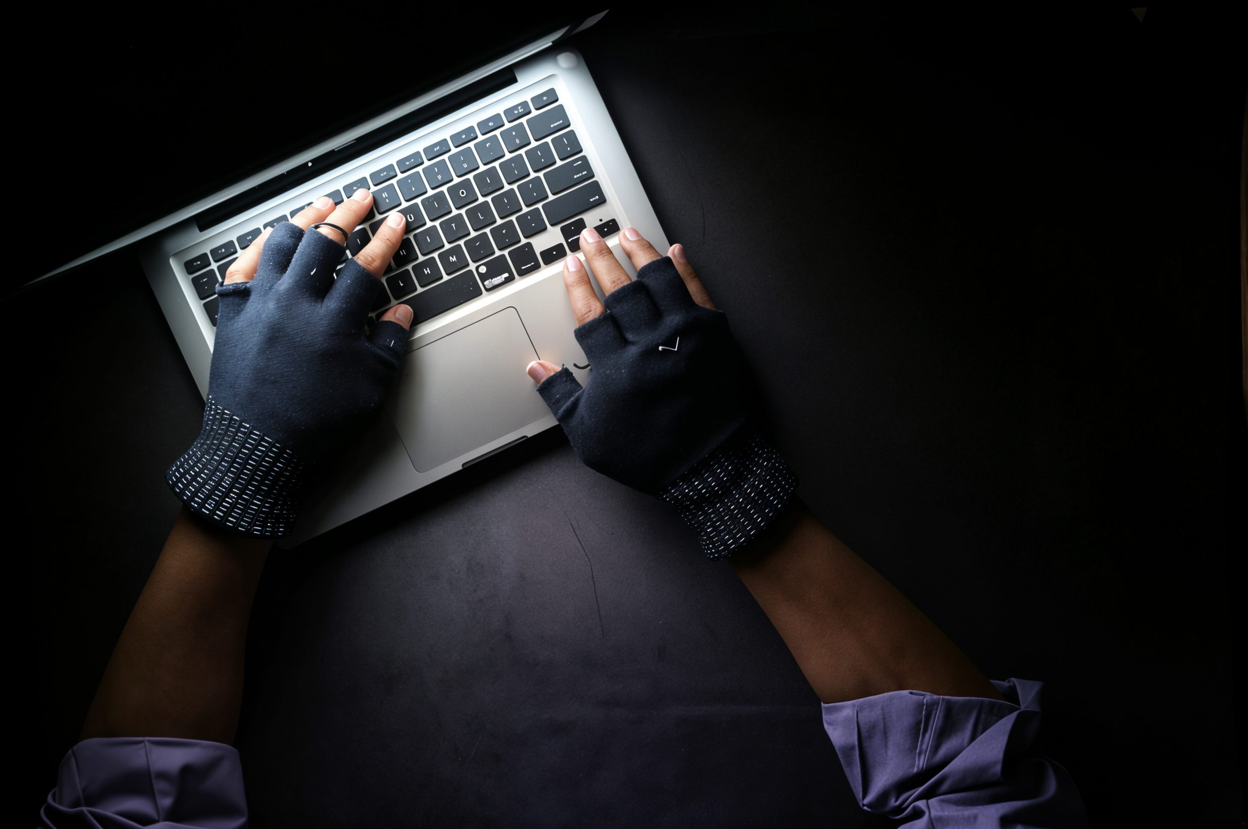 Scammer working in the dark on a laptop representing AI-driven scams