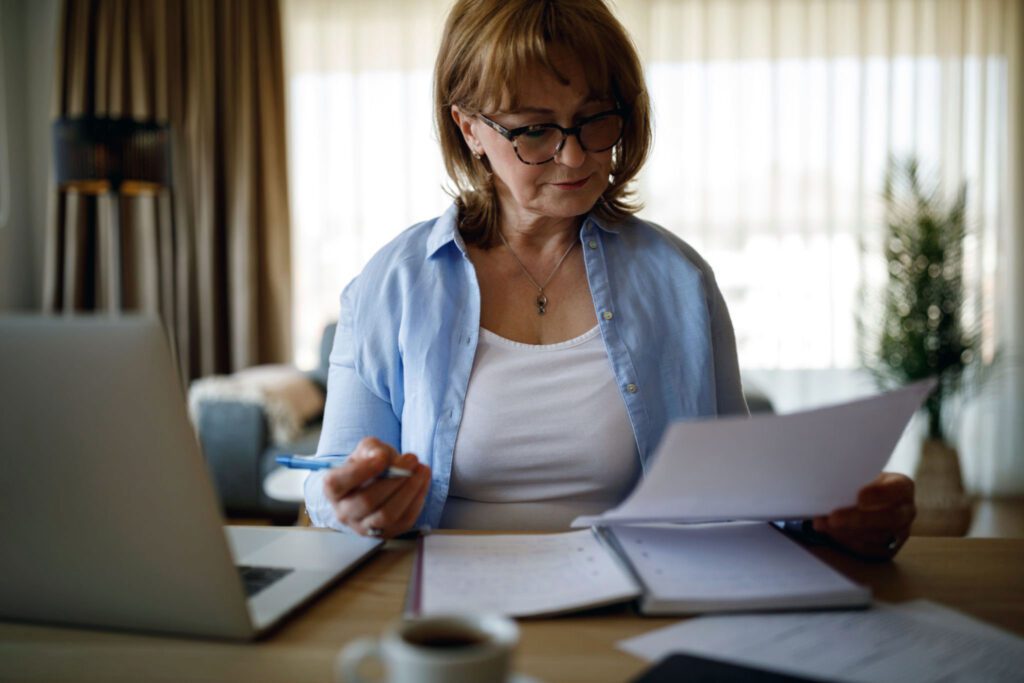 Middle aged woman going over her finances at the kitchen table considering a Roth conversion